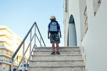 Back view of adorable little boy holding backpack go to school. Busy lifestyle outdoors journey background