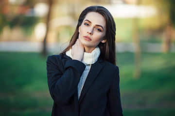 Young beautiful woman portrait posing in city park on sunset