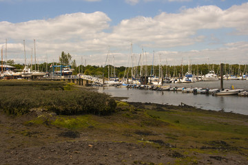 Fototapeta na wymiar The mud flats and Marina at Bucklers Hard on the Beaulieu River in Hampshire, England at low tide with boats on their moorings