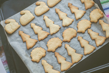 homemade Cookies in the shape of rabbit, Christmas tree, hedgehog on a pan just from the oven on parchment. Autumn and winter concept