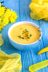 Homemade corn cream soup with thyme and pepper chili on a wooden background