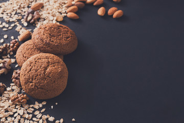 Flat lay oat cookies and nuts on dark background