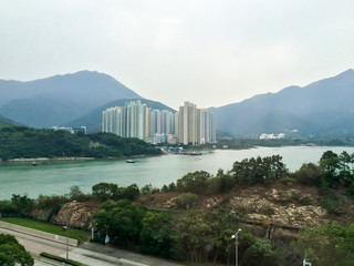 Aerial photo of tall building apartments in Hong Kong island showing density of residence in diversity with natural background of sea, mountain peak and forest from high view
