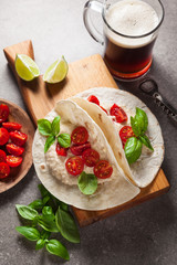 Home tortilla with hummus of white beans and beer on a gray stone table. Italian, Mediterranean style. With tomatoes and basil . dark beer