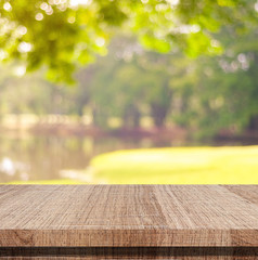 Empty wooden table over blurred tree with bokeh background, for product display montage