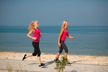 Two women exercise on beach running and rollerblade skating near sea