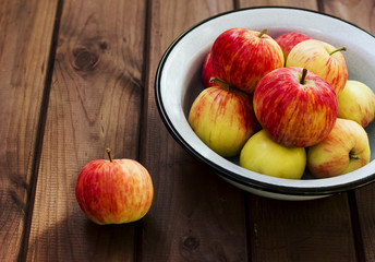 Seasonal garden red apples in metal bowl on wooden background. Fresh harvest