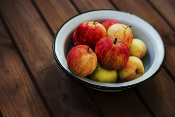 Seasonal garden red apples in metal bowl on wooden background. Fresh harvest
