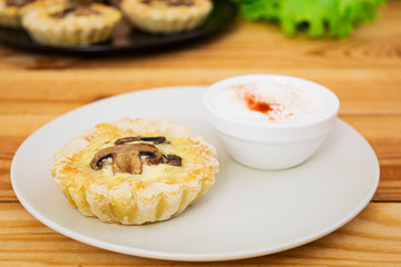 Tartlets with champignons on wooden background