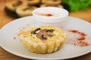 Tartlets with champignons on wooden background