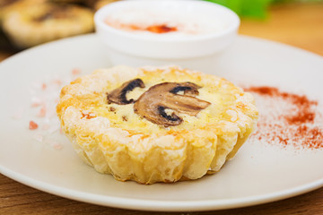 Tartlets with champignons on wooden background