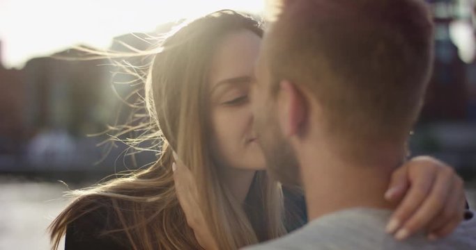 Attractive young woman giving boyfriend a tender kiss