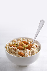 Oatmeal with nuts. Oat porridge in a bowl with spoon and almonds and pistachios.