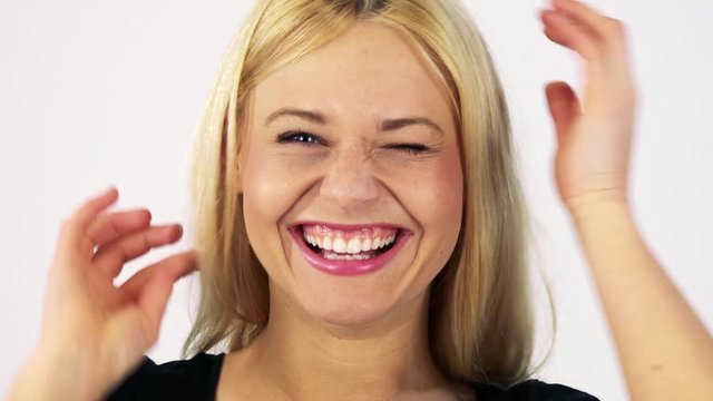 A young attractive woman makes goofy faces at the camera - face closeup - white screen studio