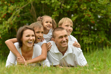smiling family lying on green grass