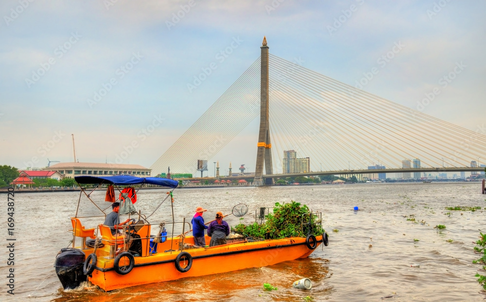 Wall mural boat cleaning the chao phraya river in bangkok, thailand