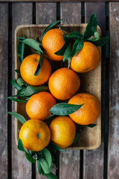 A clementines with leaves on a wooden board