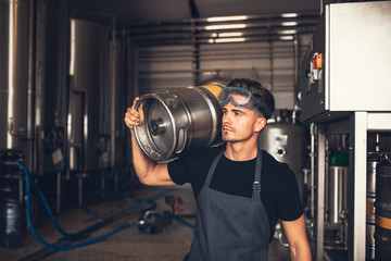 Brewer with large metal container at brewery factory