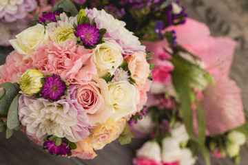 Wedding bouquet with pink, white and violet flowers - set on a wooden table. 