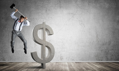 Determined banker man in empty concrete room breaking dollar figure