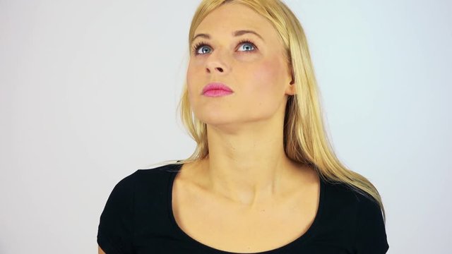 A young attractive woman uncovers her eyes and looks around in confusion - face closeup - white screen studio
