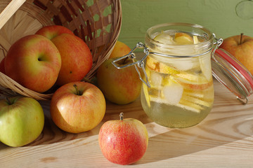 Home apple tonic with ice, scatter of apples from a wicker basket