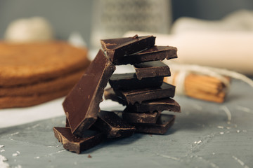 Dark chocolate and biscuit cake layer. Chocolate bar in foil on grey background. Copy space
