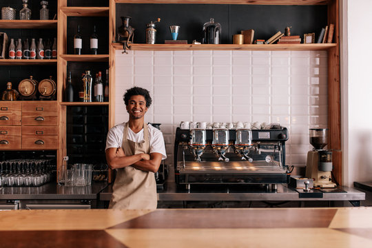 Barista in apron looking at camera and smiling