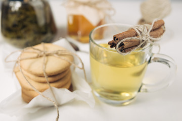 Homemade sugar cookies with honey. Ginger breads with bakery paper tied with a rope on white background. Glass cup of green hot tea 