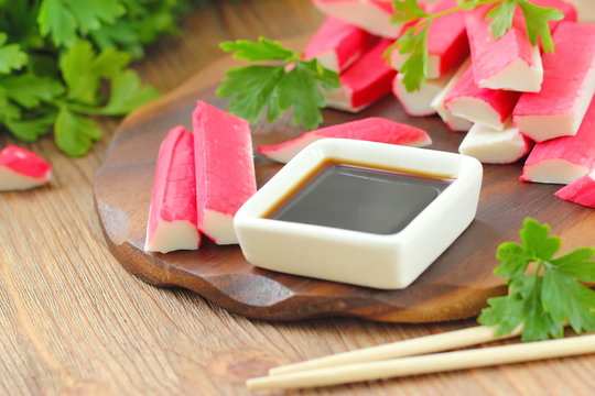 Soy sauce in a square bowl and crab sticks