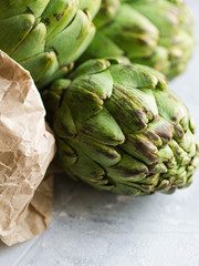 Fototapeta premium Ripe artichokes in a paper bag on a gray background