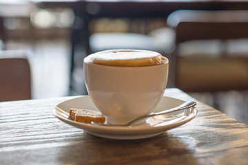 Hot cup of cappuccino and small cookie