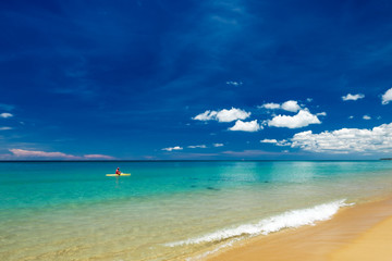 Lifesaver sitting on surfboard in water at Mai khao beach, Phuket island, Thailand.