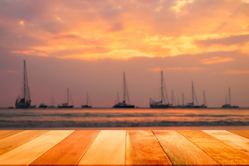 Wood plank with blurred Sailboats and sunset at Nai Harn beach, Phuket, Thailand.