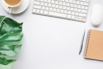 Top view modern office desk table with tropical leaves and supplies in white tone/copy space.flat...