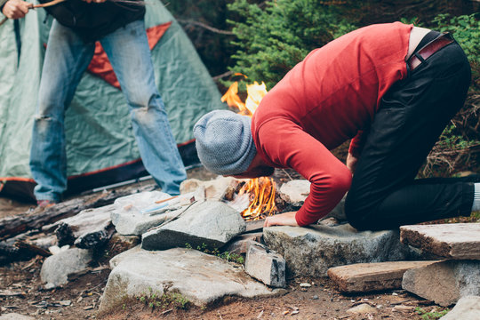 Man Blowing On Flames To Fan Campfire While On Hands And Knees