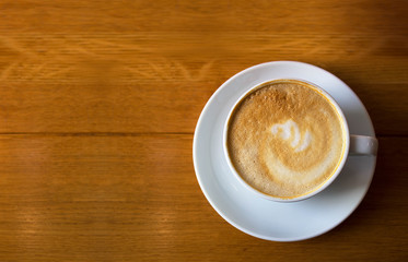 White cup of coffee on wooden table background, top view. Cappuccino latte in cafeteria