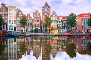 Naklejka premium Amsterdamski kanał Herengracht z typowymi holenderskimi domami i ich odbiciami podczas niebieskiej godziny porannej, Holandia, Holandia.
