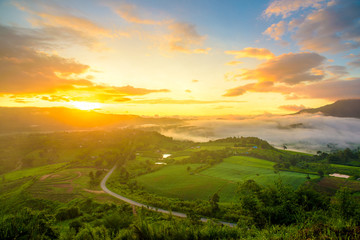 Dramatic vivid sunrise and fog with romantic cloudy sky and mountain background. Beauty of dawn sunbeam valley scene at Khao Takhian Ngo, Petchabun, Thailand.