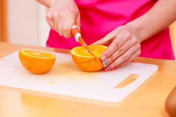 Woman housewife in kitchen cutting orange fruits