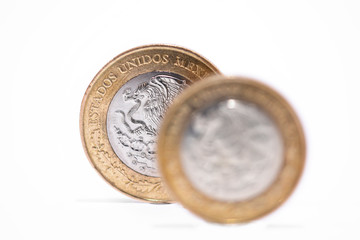 monedas mexicanas de 10 y 20 pesos sobre fondo blanco, enfocando la moneda de atras