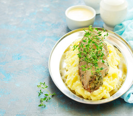 Baked pork tenderloin in herbs, with mashed potatoes and garnish.