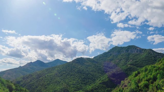  Clouds over mountains, time lapse / Blue sky with white clouds over green mountains, time lapse