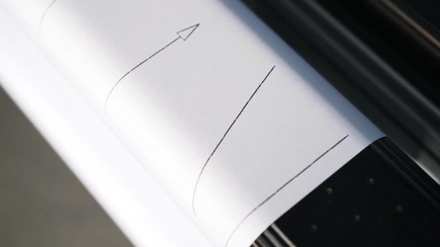 Top view of a plotter printing a blueprint in a print shop or in a company. Concept of complicated equipment. Handheld real time close up shot