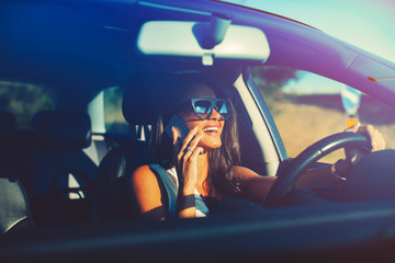 Young modern woman talking on the phone in the car