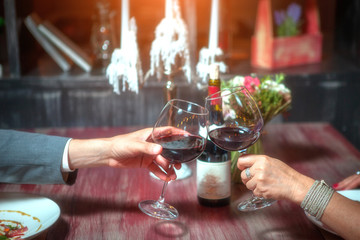 romantic couple with glasses of red wine on a date in a cozy Italian restaurant. Leisure, drinks, people and holidays concept - happy man and woman clinking glasses.