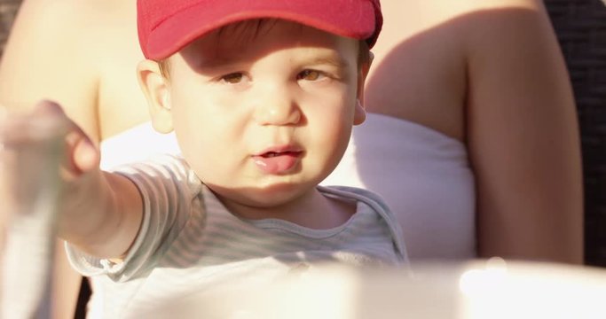 Toddler on mothers lap points towards cup of water on table