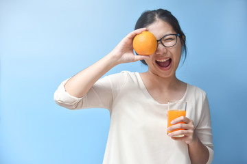 Woman holding orange on her eye with Orange juice.