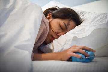 Sleepy Asian woman holding Alarm clock.