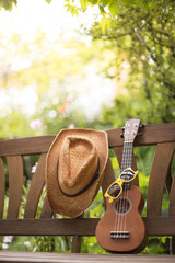 Ukulele, Strohhut und Sonnenbrille, lehnend auf Holzbank, Textfreiraum